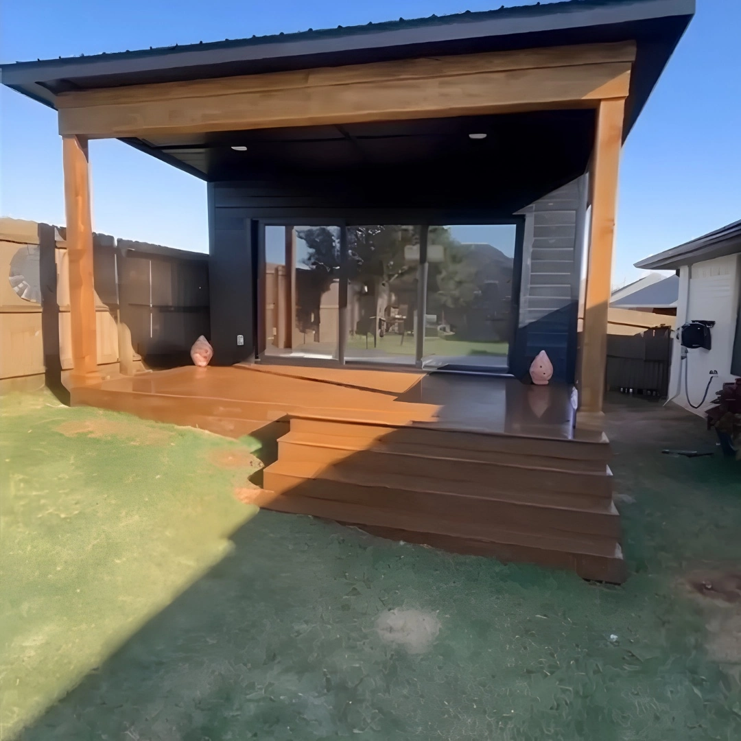 Detached backyard office studio in Yukon built by MASB Construction, with a covered porch, wide wood steps, and sliding glass doors