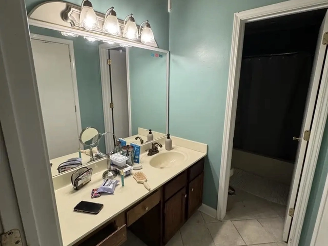 The Bethany bathroom before remodeling — dated oak vanity, cultured marble countertop, and a strip light bar over the mirror