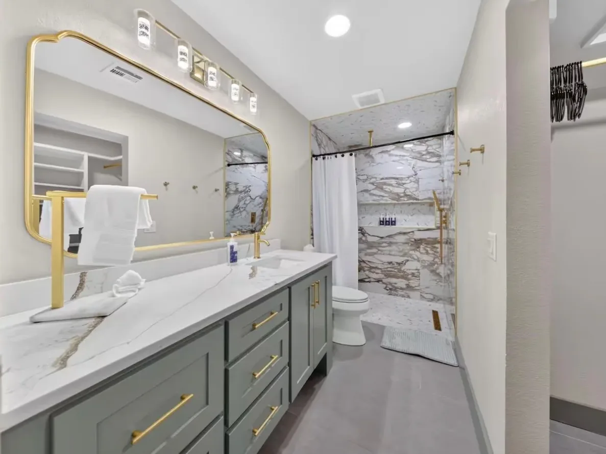 Second Piedmont bathroom with a long sage-gray vanity, gold mirror, and marble-look walk-in shower