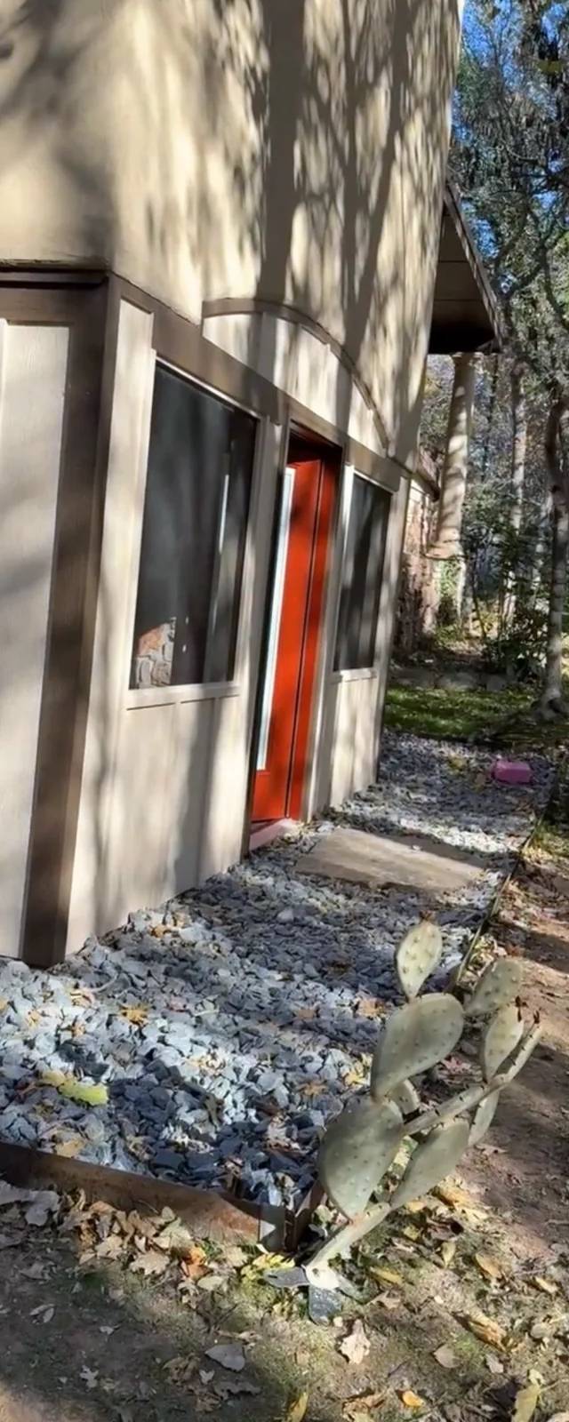 Corner of the enclosed patio with new siding, large windows, and the red entry door