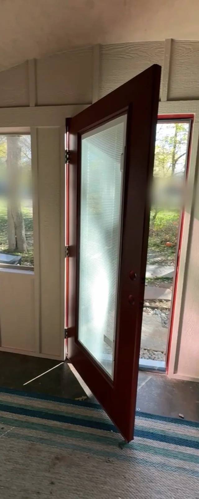 Red entry door opening into the new room, with windows on both sides
