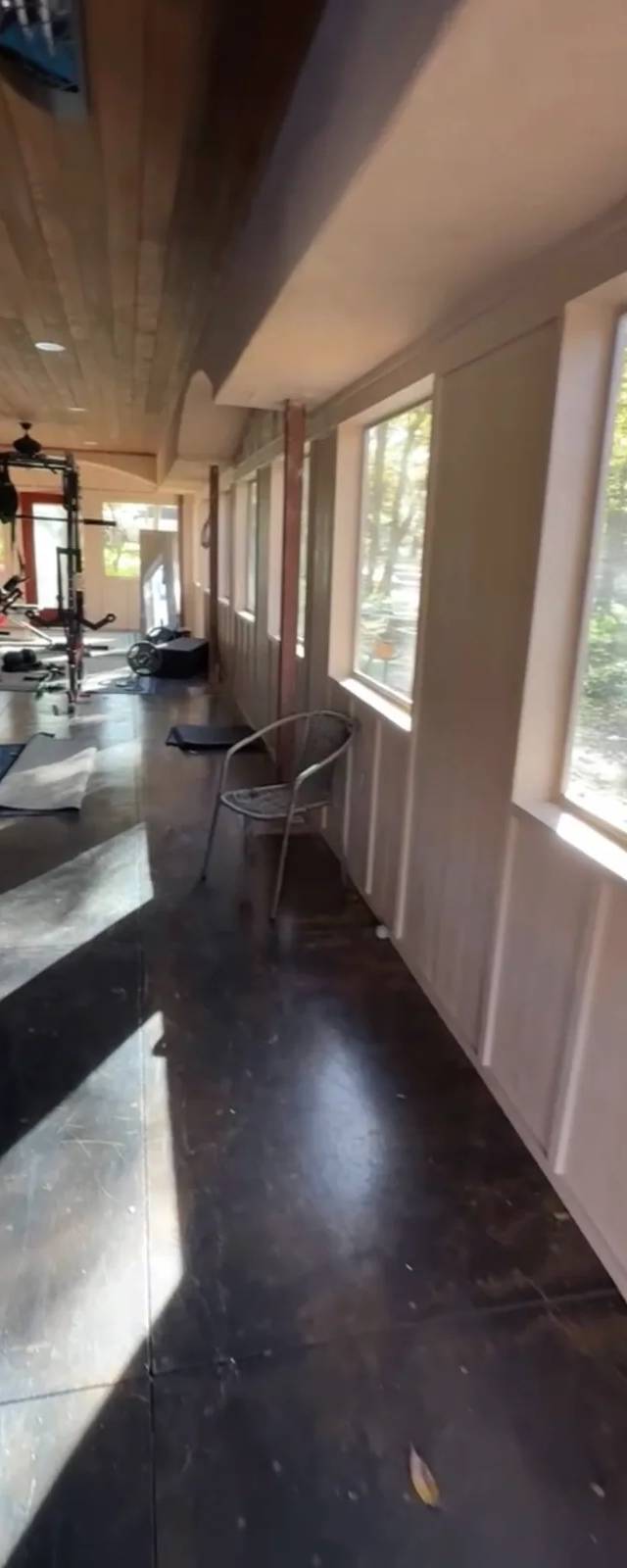 The new room in use as a gym and game room, with a stained concrete floor and a long run of windows