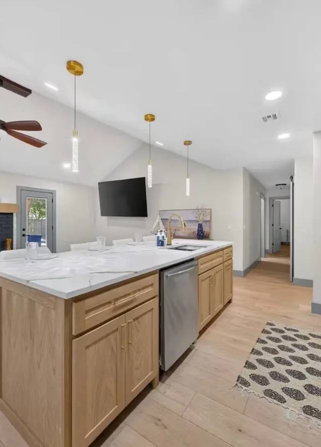 Quartz-topped white-oak island looking toward the painted brick fireplace under a vaulted ceiling in a Piedmont home