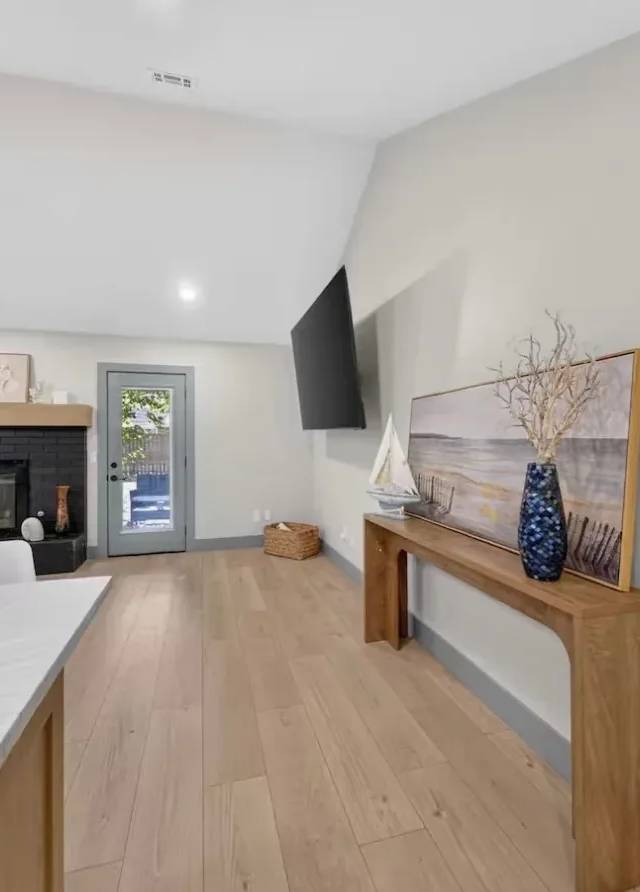 View from the kitchen island across the open living area to the fireplace and back door in a Piedmont whole-home remodel